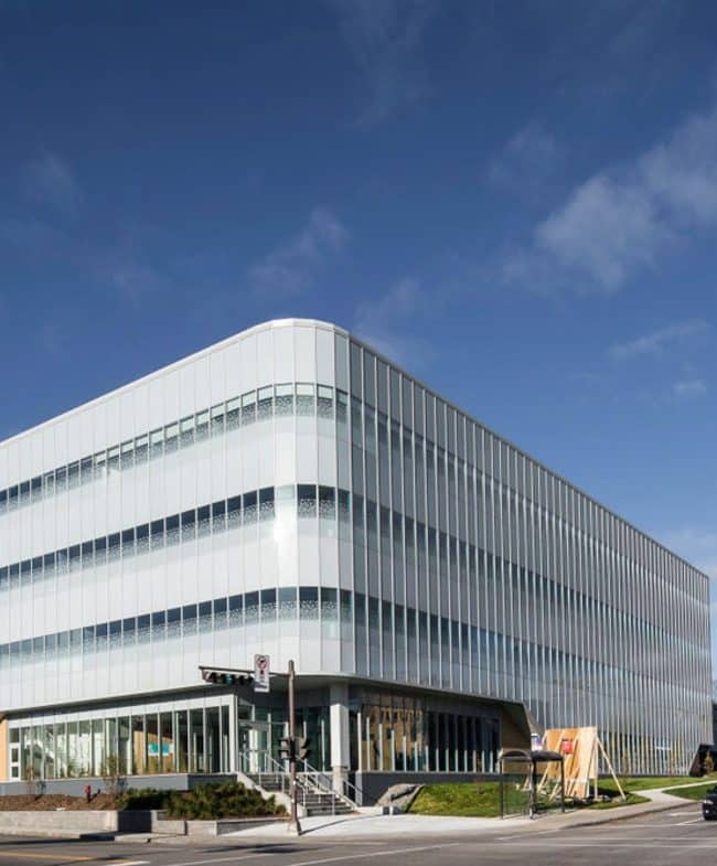 Un bâtiment moderne de plusieurs étages avec une façade de couleur claire et de grandes fenêtres.