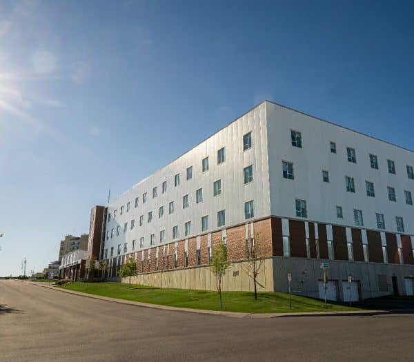 A large, modern building with many windows, under a bright sunny sky.