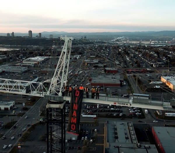 Aerial view of construction workers on a crane overlooking a city.