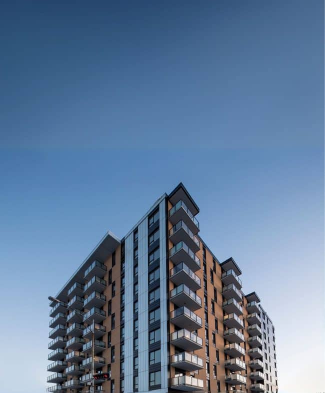 Un immeuble d'appartements moderne avec de nombreux balcons sur fond de ciel bleu clair.
