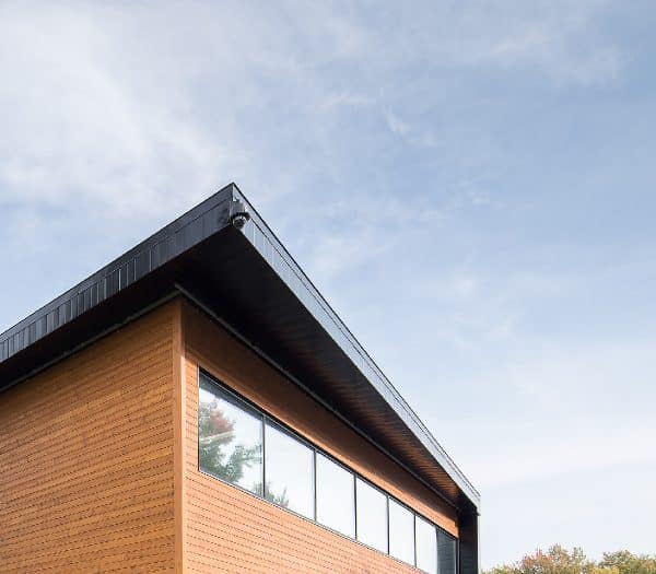 Vue en contre-plongée d'un bâtiment moderne avec un toit foncé et un revêtement en bois.