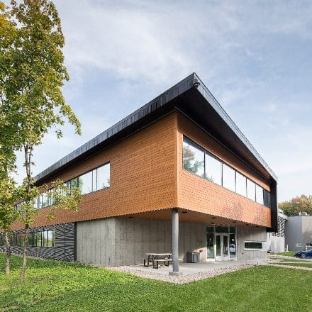 Un bâtiment moderne avec un revêtement en bois et un toit noir.