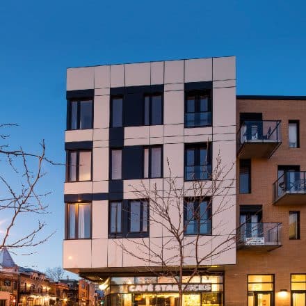 Un immeuble moderne avec une façade noir et blanc et un Starbucks au rez-de-chaussée.