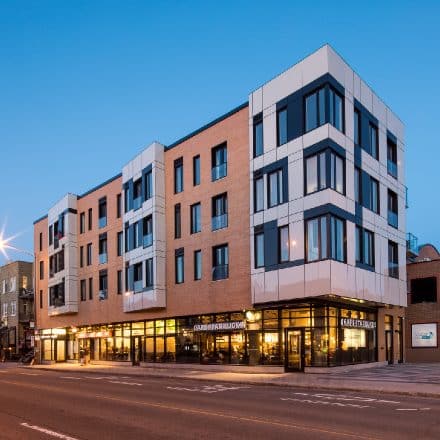 Un immeuble moderne en brique avec un Starbucks au rez-de-chaussée.