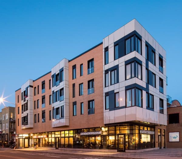 Un immeuble moderne en brique avec un Starbucks au rez-de-chaussée.