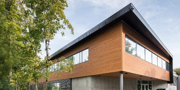 Un bâtiment moderne en bois avec de grandes fenêtres et une table de pique-nique à l'extérieur.