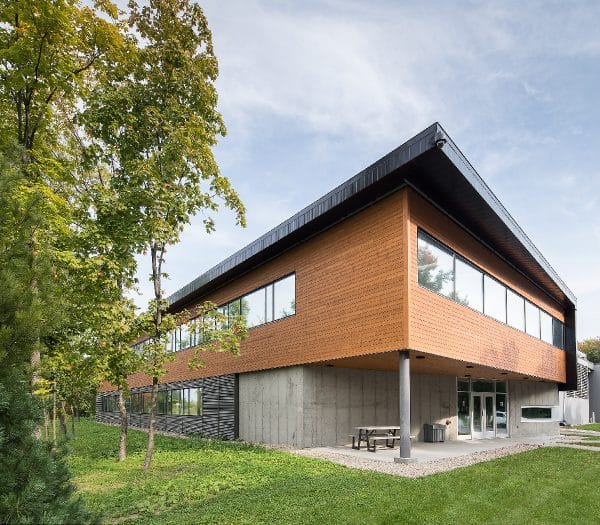 Un bâtiment moderne en bois avec de grandes fenêtres et une table de pique-nique à l'extérieur.