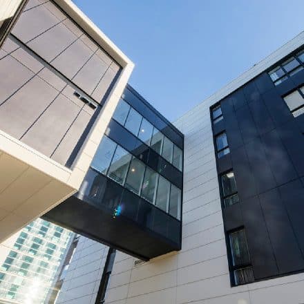 Vue en contre-plongée d'un immeuble moderne avec des panneaux sombres et clairs contrastés.