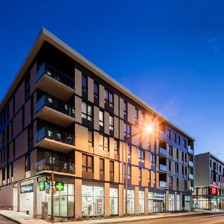 Un immeuble de plusieurs étages avec commerces et appartements au rez-de-chaussée.