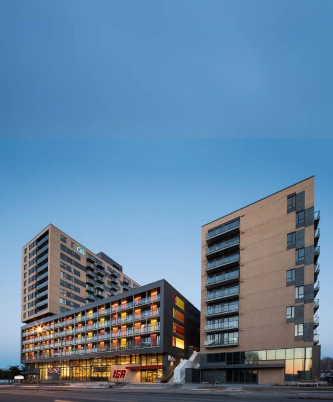 Deux immeubles d'appartements modernes avec des commerces au rez-de-chaussée, dont un supermarché IGA.