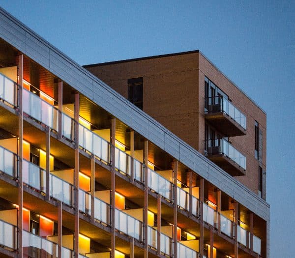 Un immeuble d'appartements moderne avec des balcons éclairés au crépuscule.