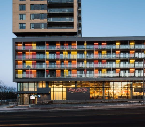 Un immeuble lumineux avec un magasin Coop au rez-de-chaussée.